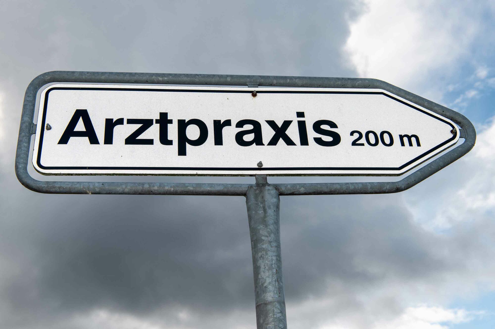 Das Foto zeigt ein Hinweisschild, auf dem steht: "Arztpraxis 200 m".